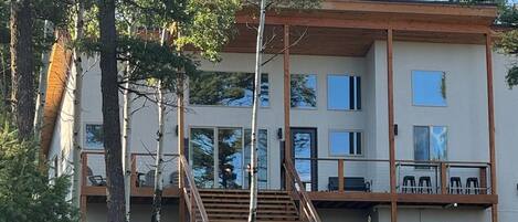 A two-story building with a wooden deck and stairs leading to a balcony.
