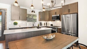 A modern kitchen with a large island, stainless steel appliances, and pendant lighting. - Alpine View: Your Getaway to Mountain Adventures (Angel Fire)