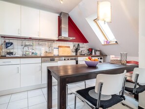 Una cocina moderna con armarios blancos, encimera de madera, campana roja y tragaluz.