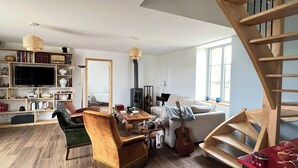 A spacious living room with a fireplace, a television, a bookshelf, and a staircase.
