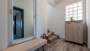 Ein Flur mit einer Bank, einem großen Spiegel, einem Holzschrank und einem Fenster.
