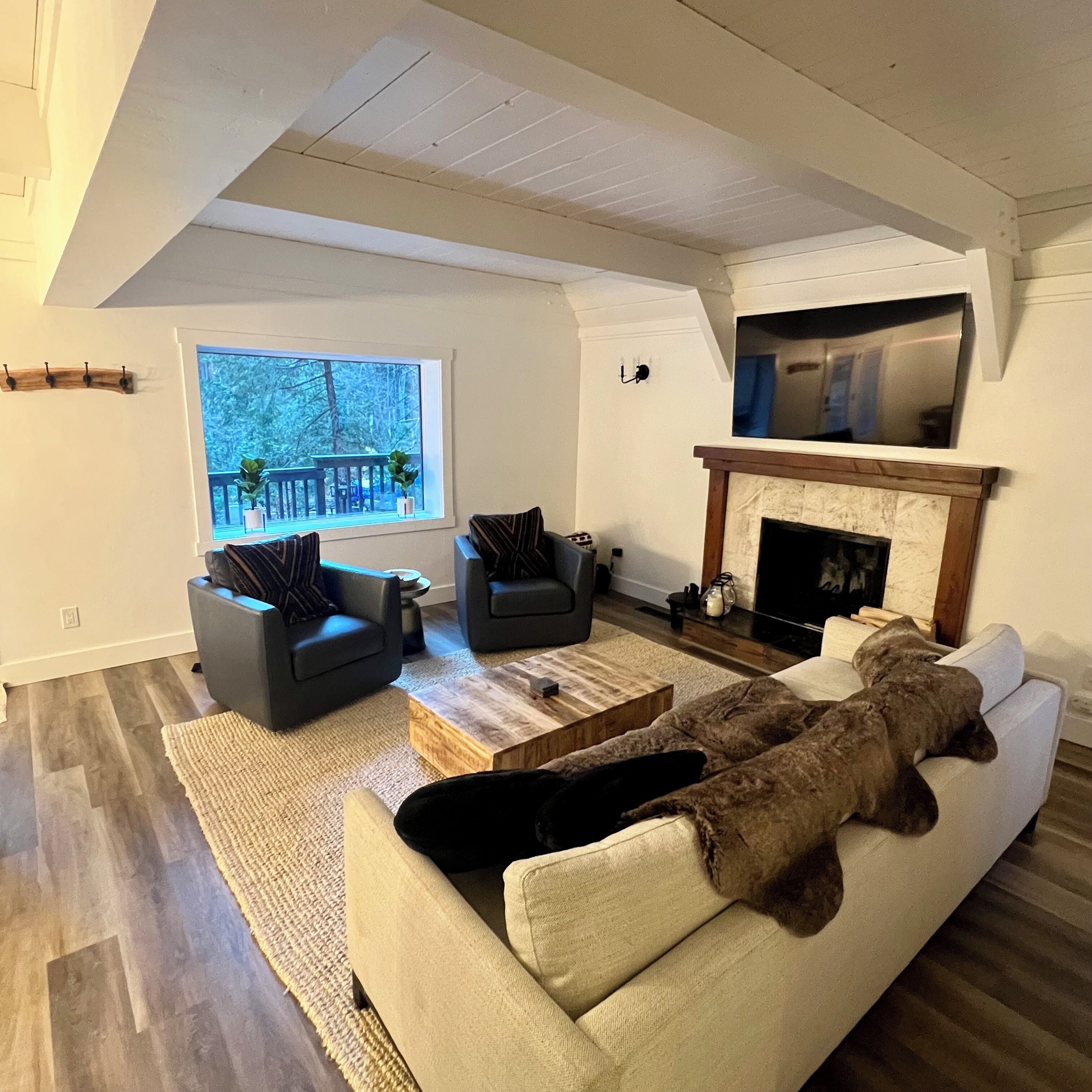Un salon avec une cheminée, deux fauteuils, un canapé et une vue sur un balcon.