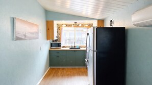 Een kleine keuken met een zwarte koelkast, een magnetron en een spoelbak.