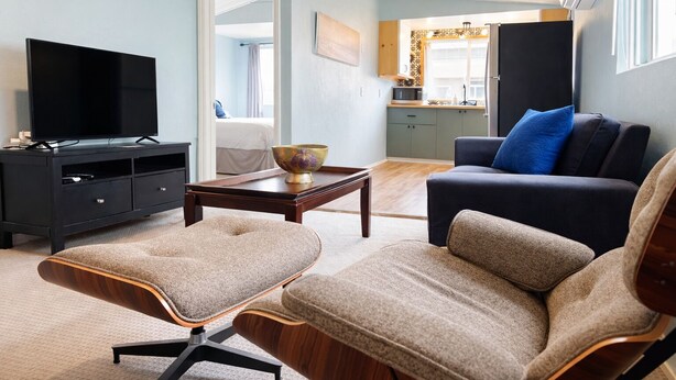Een moderne woonkamer met een flatscreen televisie, een donkergrijze bank, een bijpassende fauteuil en een houten salontafel.