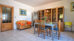 A dining area with a table, chairs, a cabinet with glass doors, a sofa, and a door.