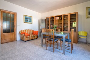 A dining area with a table, chairs, a cabinet with glass doors, a sofa, and a door.