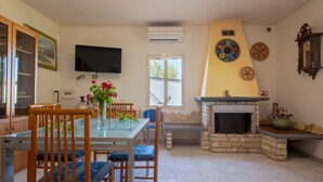 A dining area with a table, chairs, a TV, a fireplace, and decorative plates on the wall.