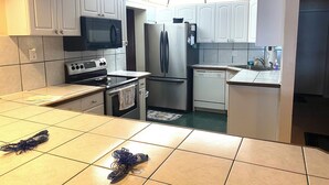 A compact kitchen with white cabinets, a microwave, a refrigerator, an oven, and a dishwasher. - Lake Placid Vacation Destination for the whole family! (Lake Placid)
