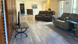 A spacious living room with a wooden ceiling, a fireplace, and a large window. - Lake Placid Vacation Destination for the whole family! (Lake Placid)