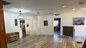 A spacious living room with hardwood flooring, a ceiling fan, and a dining area with a wicker chair. - Lake Placid Vacation Destination for the whole family! (Lake Placid)