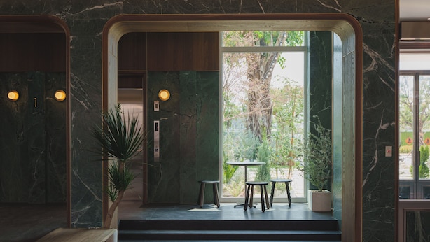 A modern interior with a marble wall, a wooden bench, and a small table with stools. - PAPO'A HARBOR HOTEL (Kaohsiung)