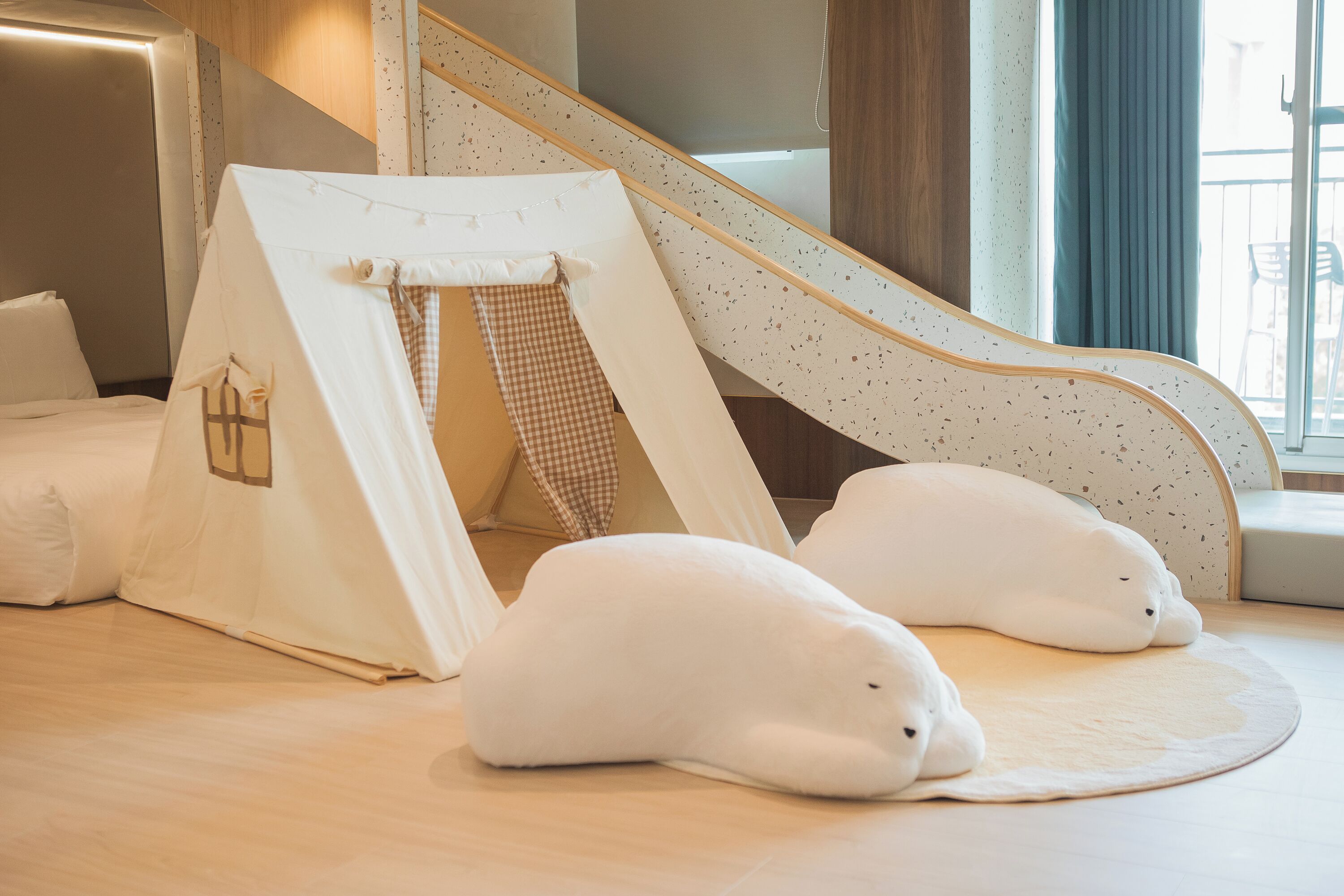A room with a tent-like structure, a wooden floor, and a window with curtains.