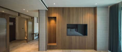 A modern hotel room with a large bed, a mounted TV, and a wooden accent wall.