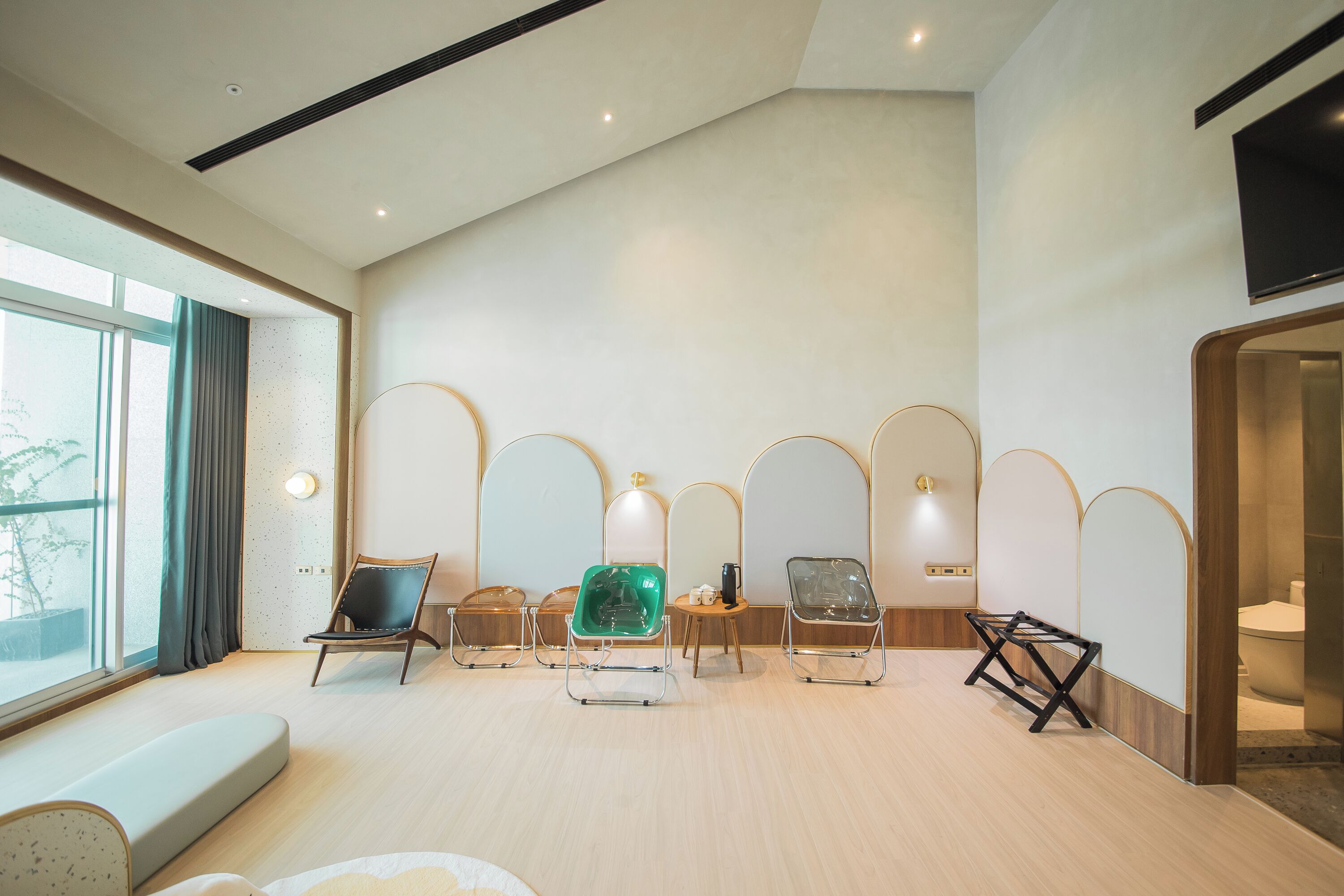 Um quarto amplo com uma grande janela, um sofá e várias cadeiras.