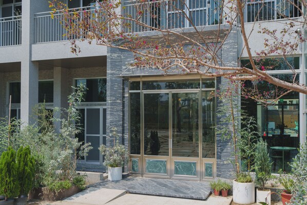 A modern building with a glass entrance, potted plants, and a balcony. - PAPO'A HARBOR HOTEL (Kaohsiung)