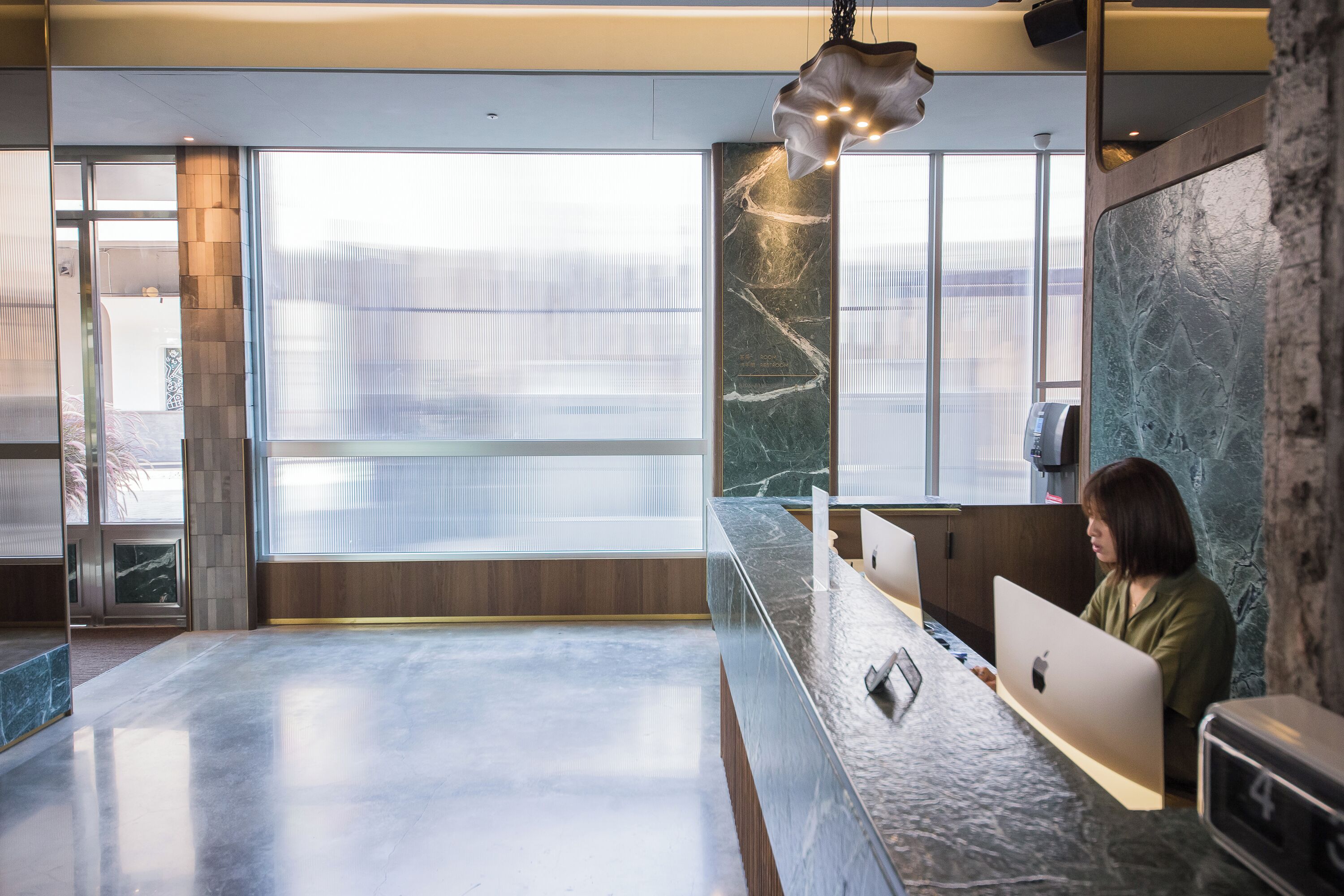 A modern reception area with a marble counter, large windows, and a view of the city.
