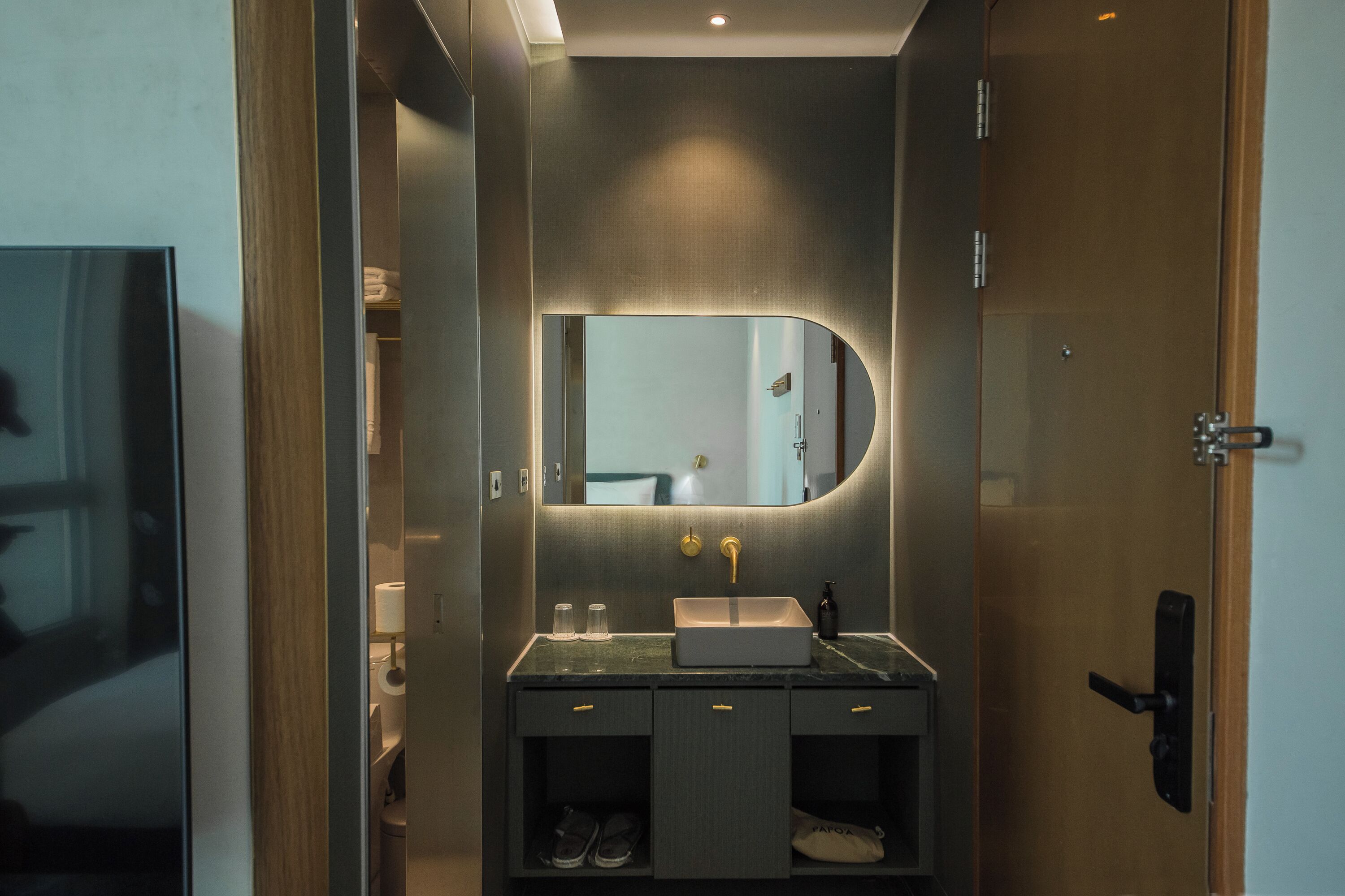 Un baño moderno con tocador, lavabo y espejo.