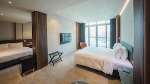 A hotel room with a large bed, a smaller bed, a TV, a desk, and a window with a city view. - PAPO'A HARBOR HOTEL (Kaohsiung)
