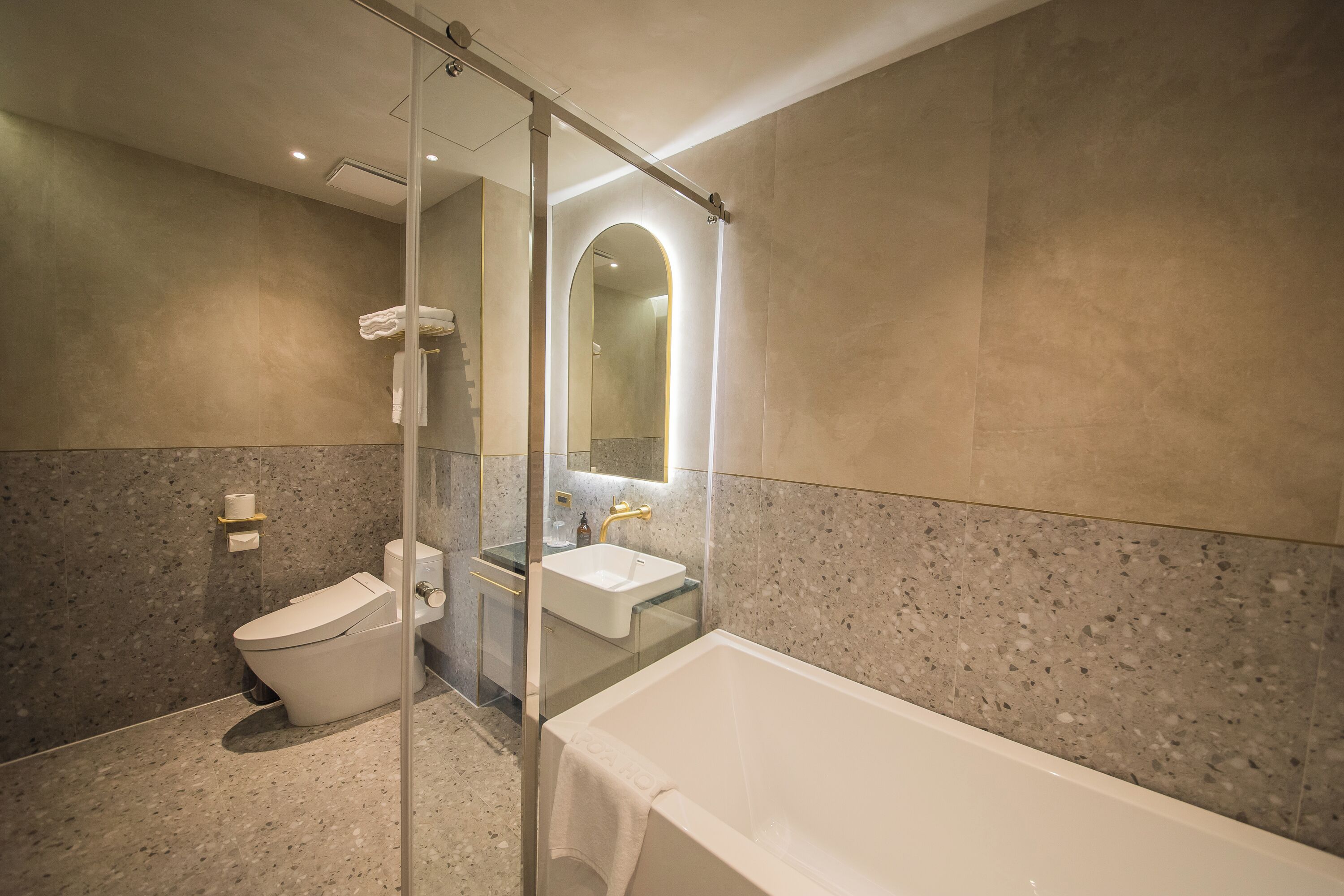 A modern bathroom with a glass-enclosed shower, a toilet, a sink, and a bathtub.