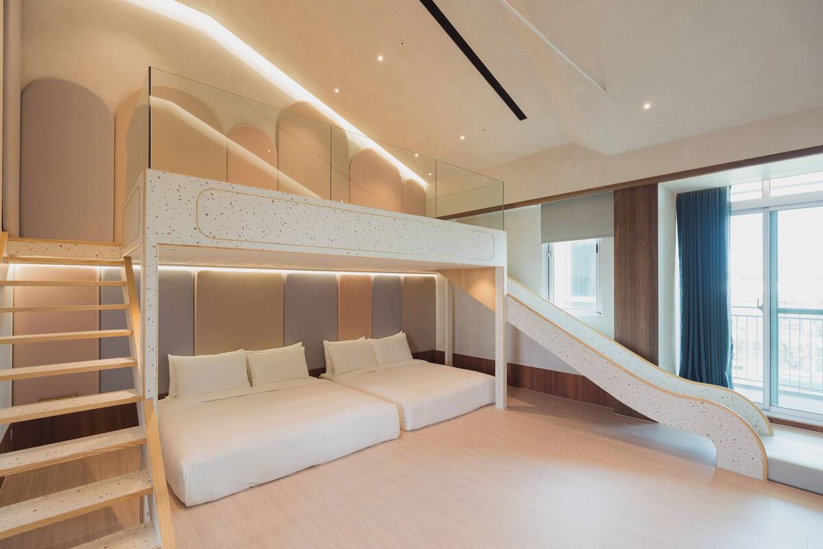 A modern interior with a bunk bed, a staircase, and a large window.