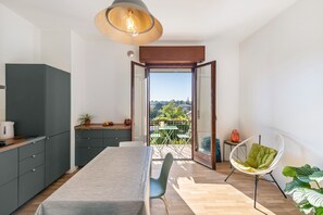 A modern kitchen with a dining area, a view through an open door, and a seating area with a chair. - Apartment 'La Casetta' with balcony and air conditioning (Verona)