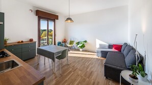 Une cuisine moderne avec un coin repas, un canapé gris et un balcon offrant une vue agréable.