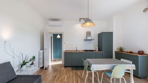 Une cuisine moderne avec un coin repas, un canapé gris et une petite table d’appoint agrémentée de plantes.