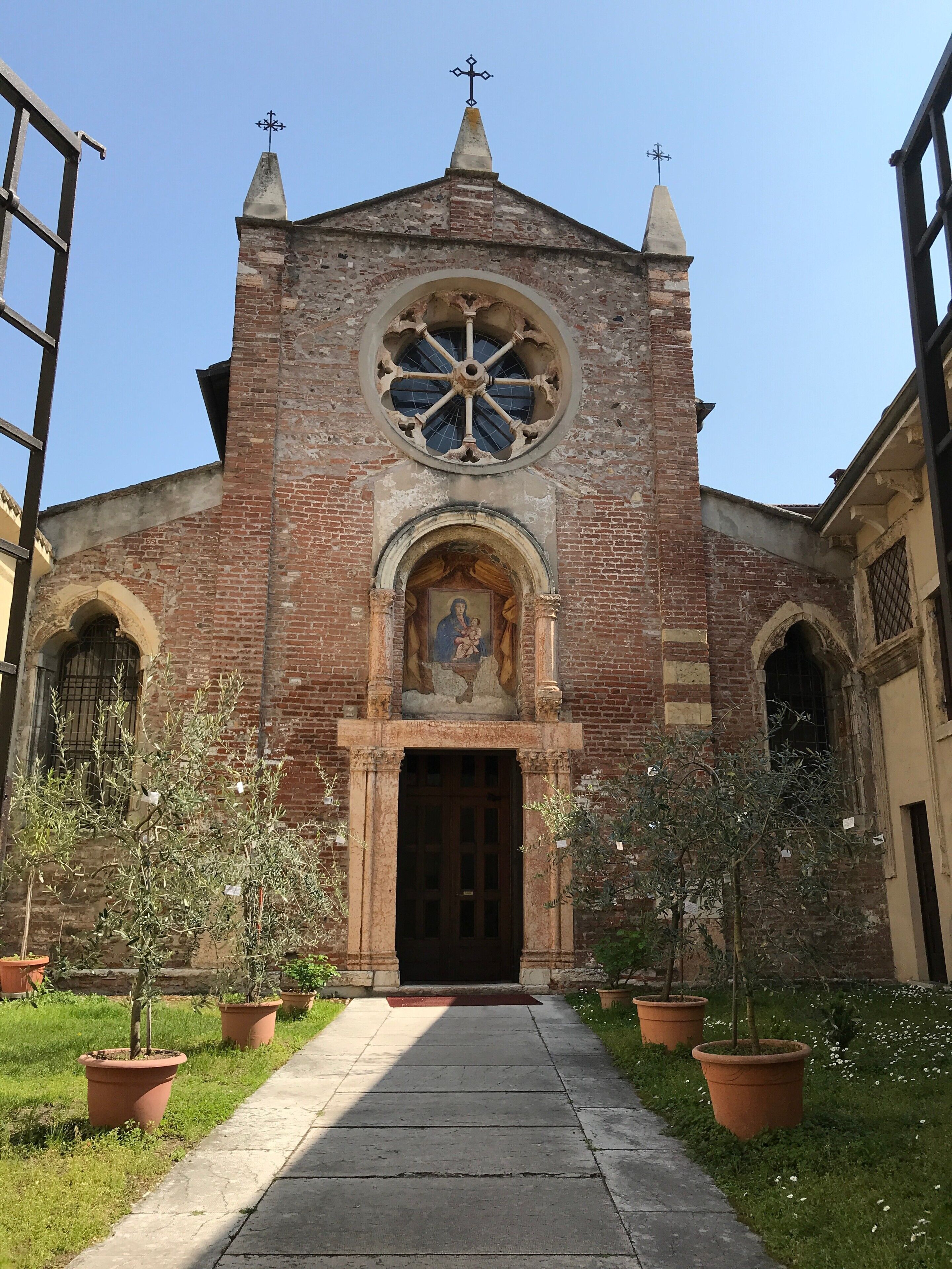 A historic church with a large circular window, a weather vane, and a statue above the entrance.