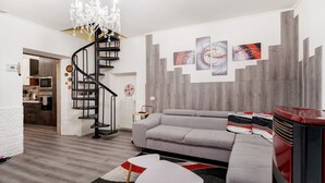 Ein modernes Wohnzimmer mit einem grauen Sofa, einem weißen Couchtisch, einer schwarzen Wendeltreppe und abstrakter Wandkunst.