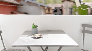 Ein Balkon mit einem kleinen Tisch, einem Blumentopf und einem Selfie-Stock.