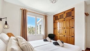 A hotel room with two beds, a wooden wardrobe, a window with curtains, and a lamp. - Villa 'Casa Crystal' with Mountain View, Wi-Fi and Air Conditioning (Javea)