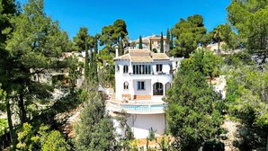 A white villa with a circular balcony, surrounded by trees and hills. - Villa 'Casa Crystal' with Mountain View, Wi-Fi and Air Conditioning (Javea)