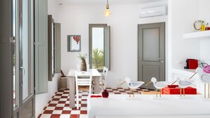 Una cocina compacta con piso a cuadros, una mesa de comedor, sillas, una lámpara colgante y una puerta.