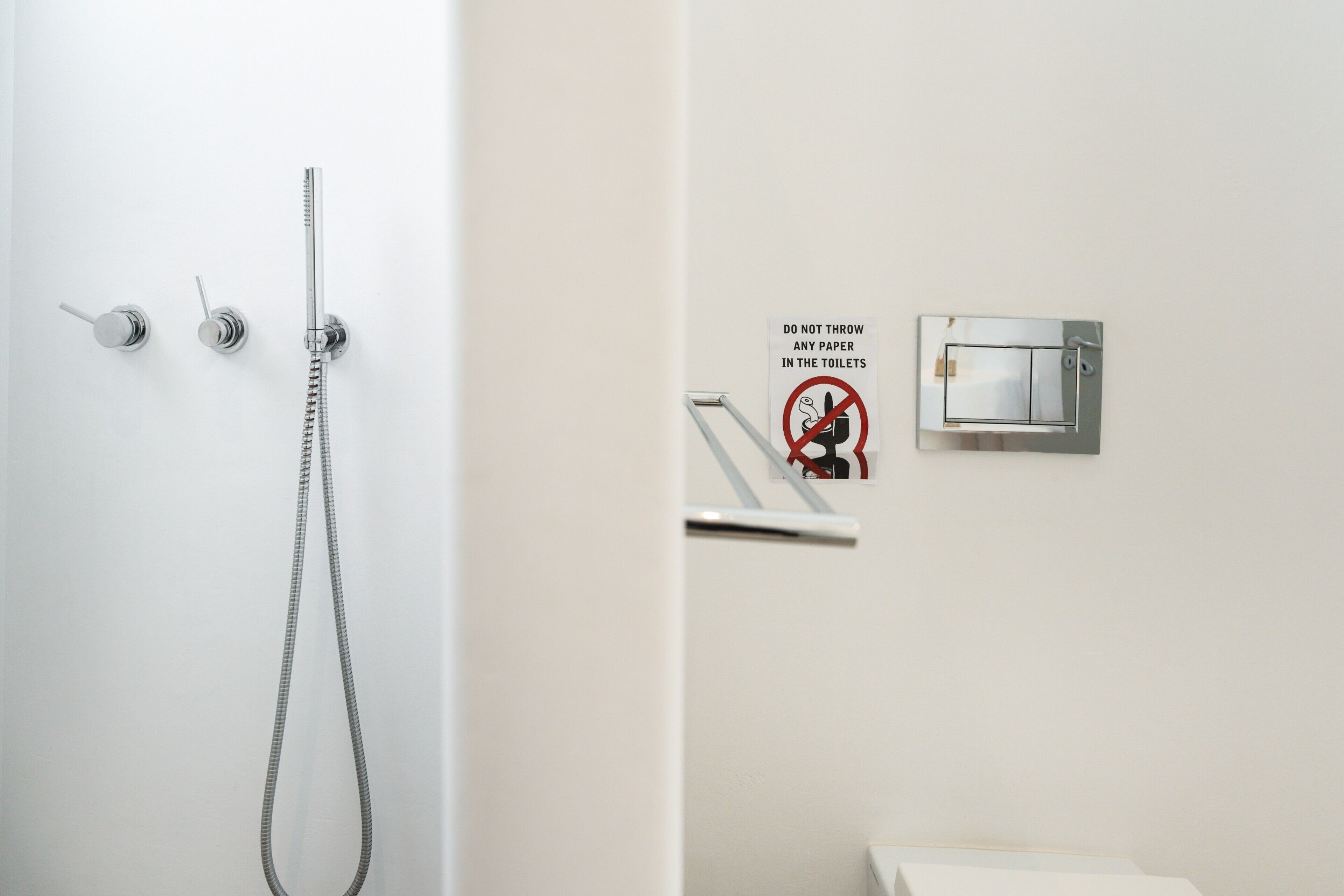 A bathroom with a shower, a toilet, and a sign prohibiting paper disposal in the toilet.