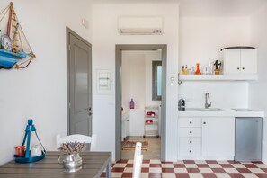 Una cocina compacta con refrigerador, lavamanos y gabinetes blancos.