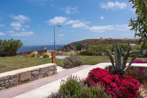 A landscaped garden with a stone pathway, a large agave plant, and vibrant flowers. - Apartment 'Moon Kiss' with Sea View, Wi-Fi and Air Conditioning (Milos)