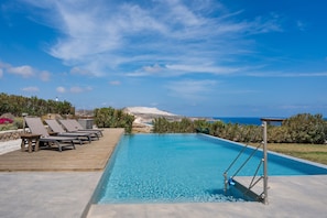 A swimming pool with lounge chairs and a lifeguard stand. - Apartment 'Moon Kiss' with Sea View, Wi-Fi and Air Conditioning (Milos)