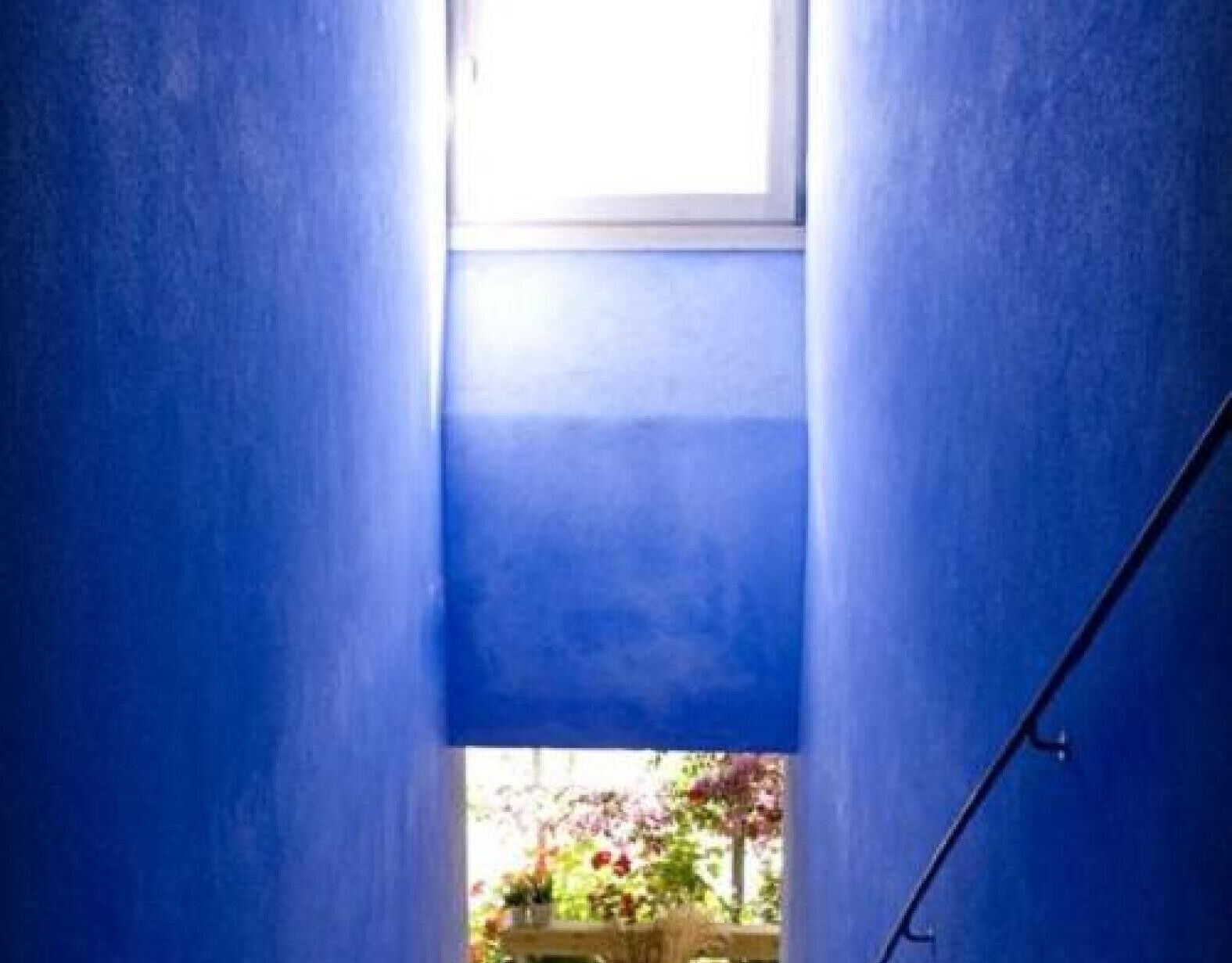 Un estrecho pasaje con paredes azules que conduce a una ventana.