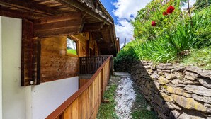 Una cabaña de madera con balcón, pared de piedra y un sendero de grava.