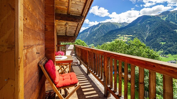 Un balcón de madera con vistas a las montañas.