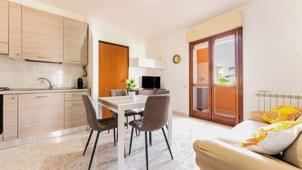 A modern kitchen with a dining area, a sofa, and a view of the outside.