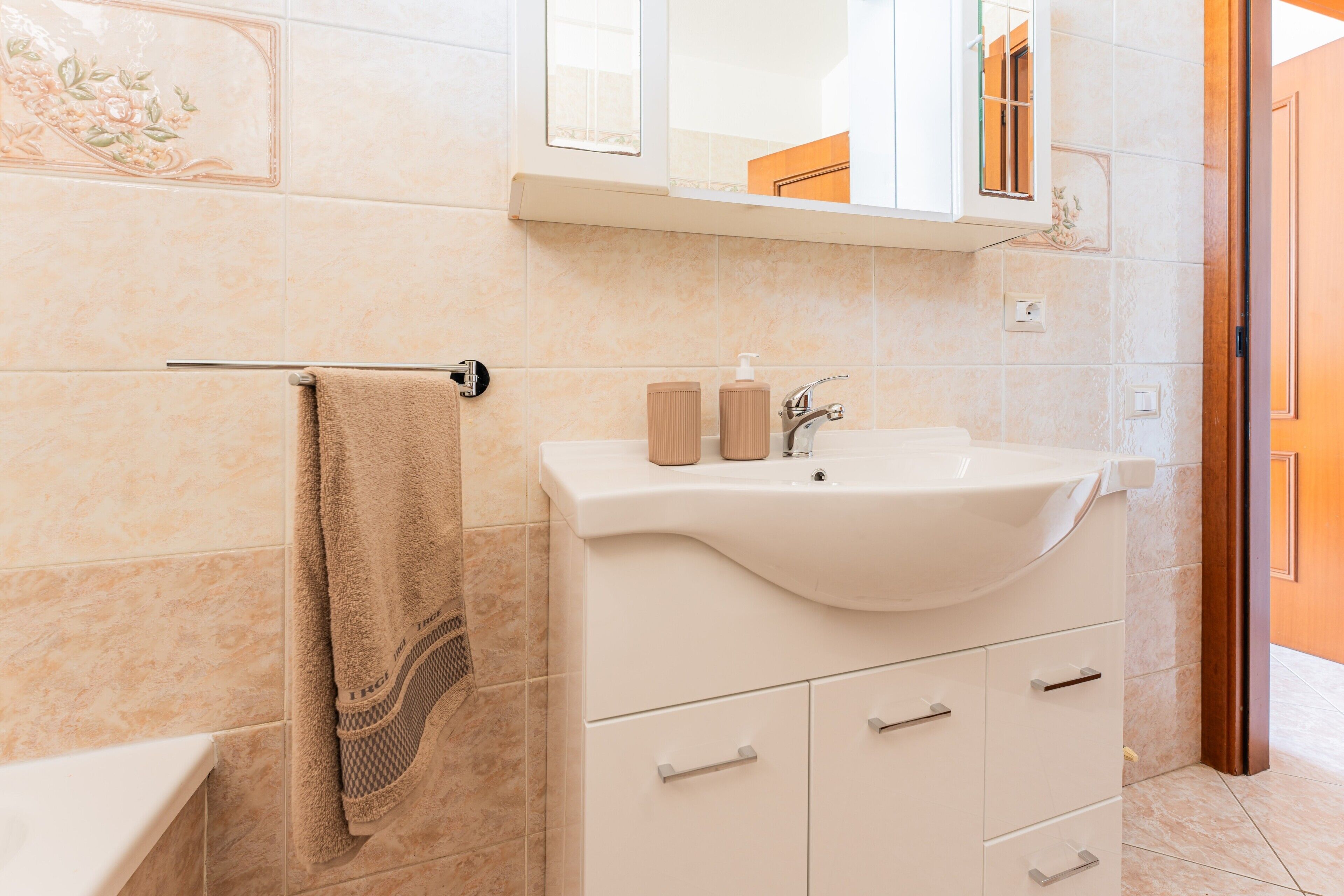 A bathroom with a beige towel, a sink, and a cabinet.