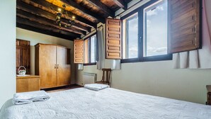 Ein Schlafzimmer mit einem großen Bett, einem Holzschrank und einem Fenster mit Fensterläden.