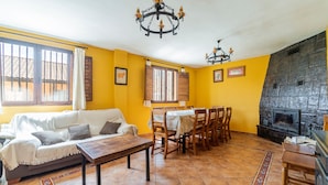 Ein Wohnzimmer mit Sofa, Esstisch, Stühlen, Kamin und einer Chandelier.