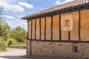 Un edificio de piedra con tejado de baldosas y una ventana pequeña.