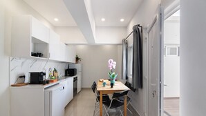 Cocina compacta con mesa de comedor, sillas y una pequeña isla con electrodomésticos.
