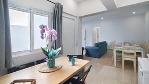 Una sala de estar moderna con comedor, un sofá azul y una mesa con sillas.