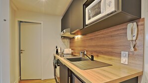 Cocina compacta con encimera de madera, pileta de acero inoxidable y horno microondas.