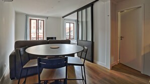 Una sala de estar moderna con una mesa redonda, dos sofás y un ventanal corredero que da a un balcón.