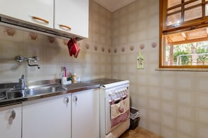 A kitchen with white cabinets, a stainless steel sink, and a white stove. - Villa Rosa, Relax Place – Sea View Apartment with Wi-Fi and Air Conditioning (Conversano)
